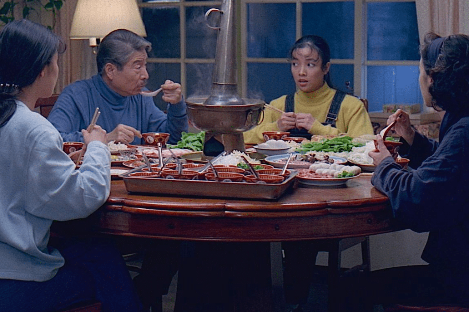 Bốn người quây quần bên mâm cơm nóng hổi với lẩu và nhiều món ăn