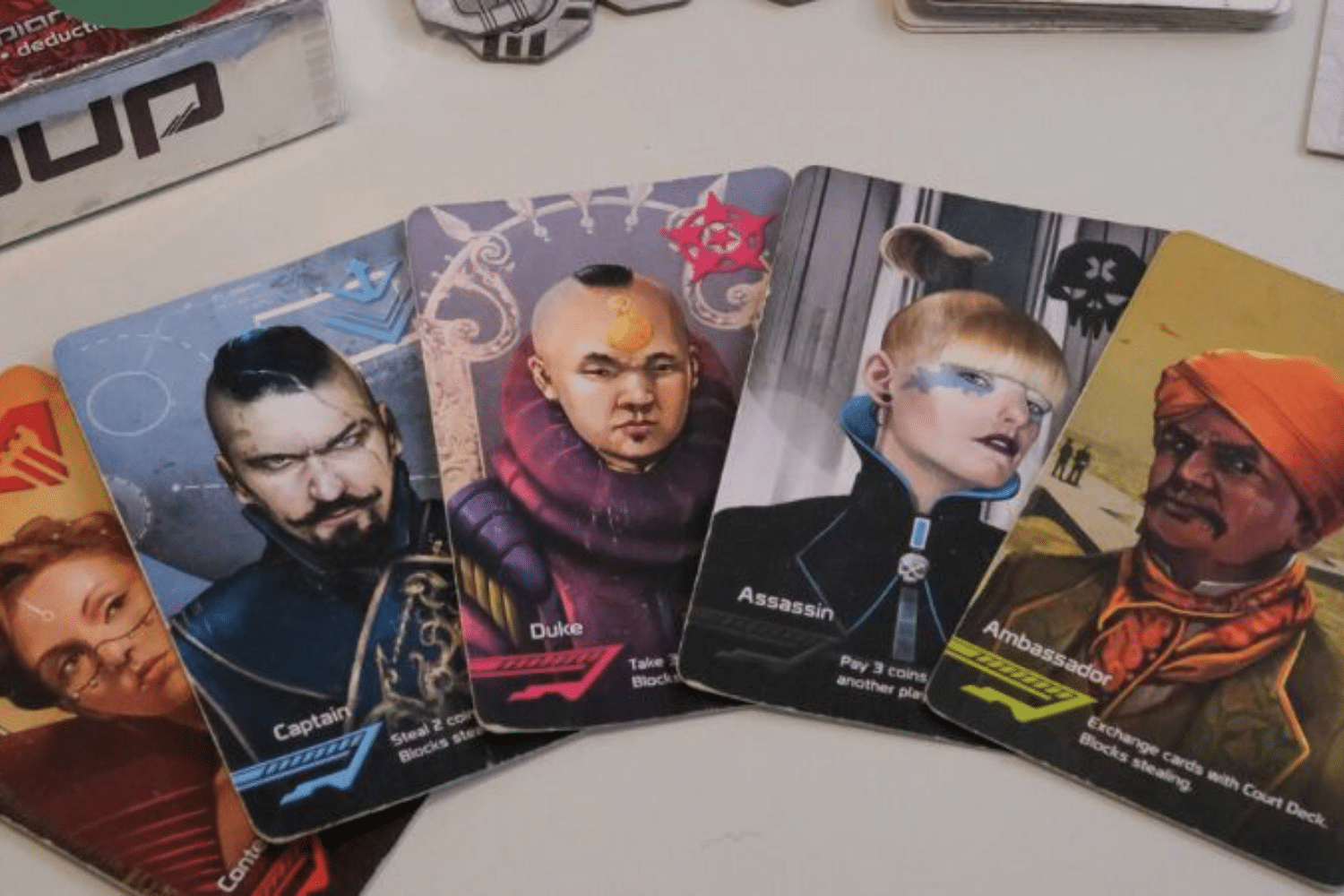 Bộ bài board game với các nhân vật Captain Duke Assassin và Ambassador được trải trên mặt bàn