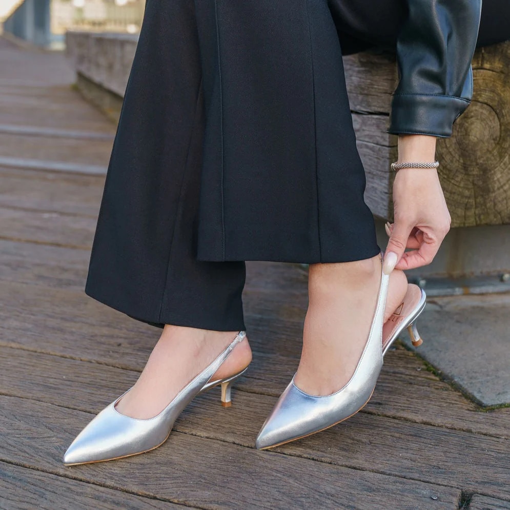 Người phụ nữ đang xỏ đôi giày cao gót bạc ánh kim sang trọng